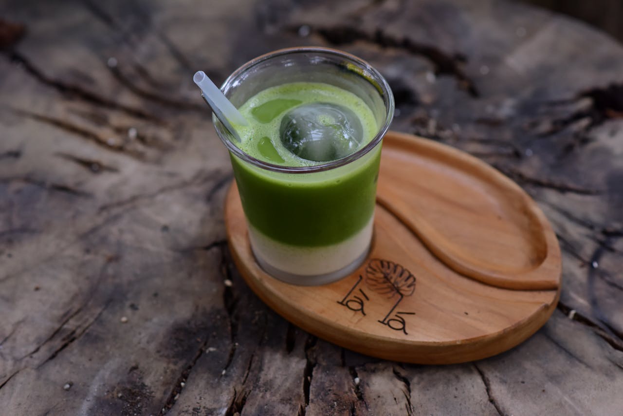 Iced matcha latte with ice ball on rustic wooden tray, perfect for a refreshing break.