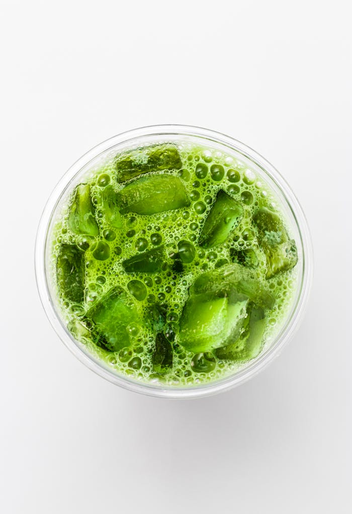 Top-down shot of a refreshing iced matcha latte with vibrant green color and ice cubes.